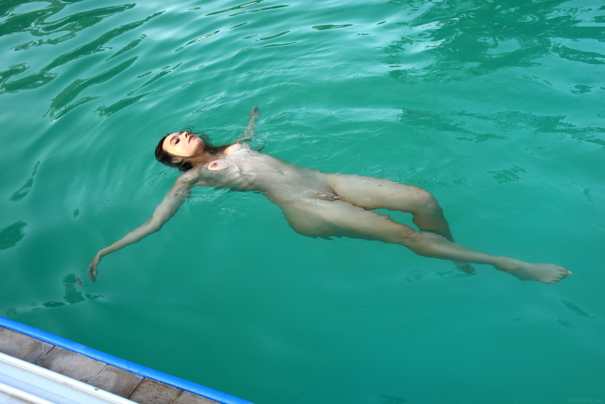 Голая женщина купается в бассейне